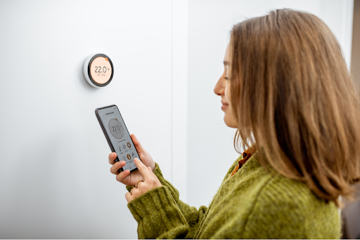 A woman using a smart thermostat in a Simi Valley, CA home.