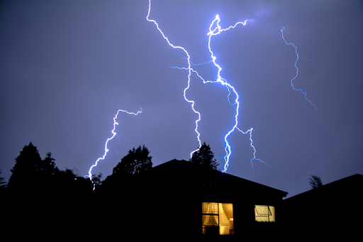 Lightning striking behind a house.