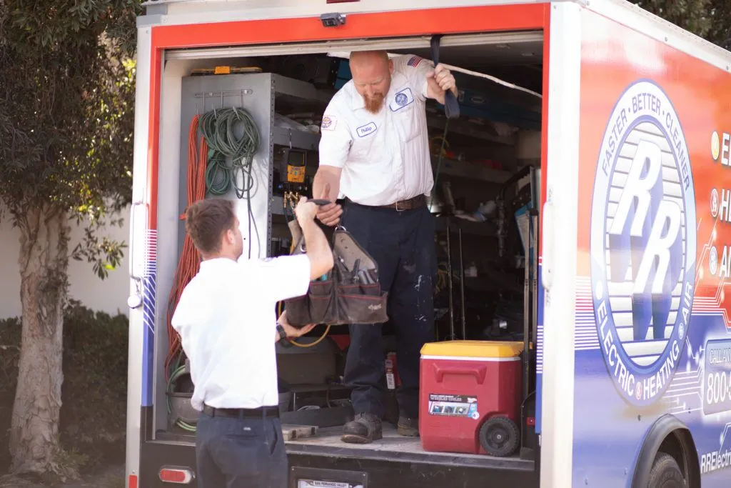 Two technicians taking equipment out of a van